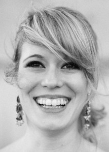 Thalia Mostow Bruehl smiles in a black and white headshot. She wears large earrings and her blond hair falls diagonally across her face. 