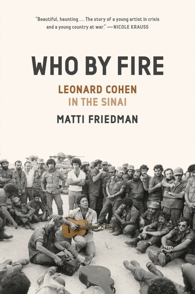 Book cover for Who By Fire - Leonard Cohen in the Sinai by Matti Friedman. The background is a pale pink-white color. A black and white photo of a large group of are men are in the foreground of the cover. There is a military tank behind them. A man in the front holds a guitar and sings. The guitar is the only thing that has color.