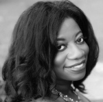 Black and white photo of Michelle D. Commander. She is a Black woman with shoulder length, lightly curled hair. She is looking over her shoulder and smiling at the camera. 