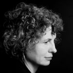 Black and white photo of Jennifer Anne Moses. She is looking to the left, away from the camera. She has short curly hair.