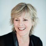 Helene Dorion is laughing and looking away from the camera. She has short, straight gray hair. She is wearing a black blazer.