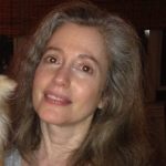 Alexander is looking at the camera and smiling. She has brown-gray hair.