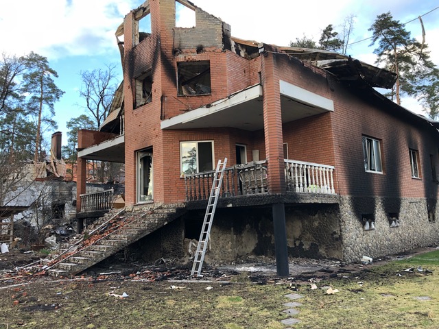 The other side of the burnt red brick building. More signs of fire that ate the balcony, collapsed the roof, emanated from the windows and vents, the house goes nowhere, it's top is gone, windows showing sky where walls once stood. 